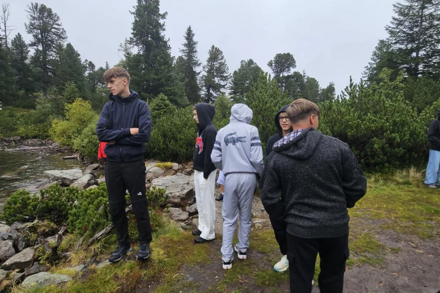 Jugendliche am Ufer eines Bergsees mit Nadelbäumen im Hintergrund
